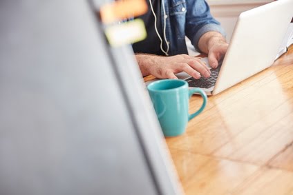 Image représentant une personne en train de boire un café et en train de gérer ses comptes sur un PC portable